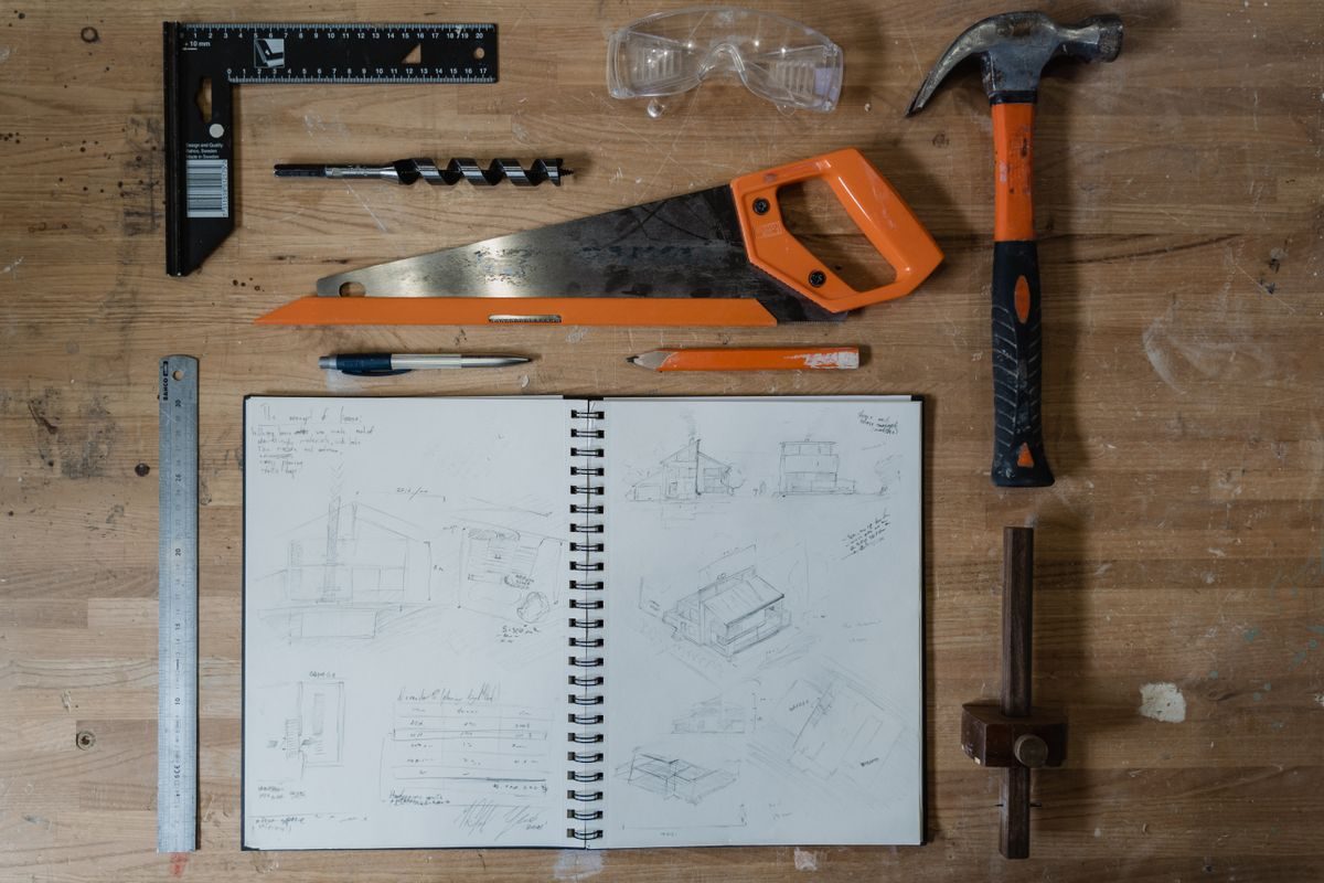 A notebook and a set of hand tools laid out on a workbench