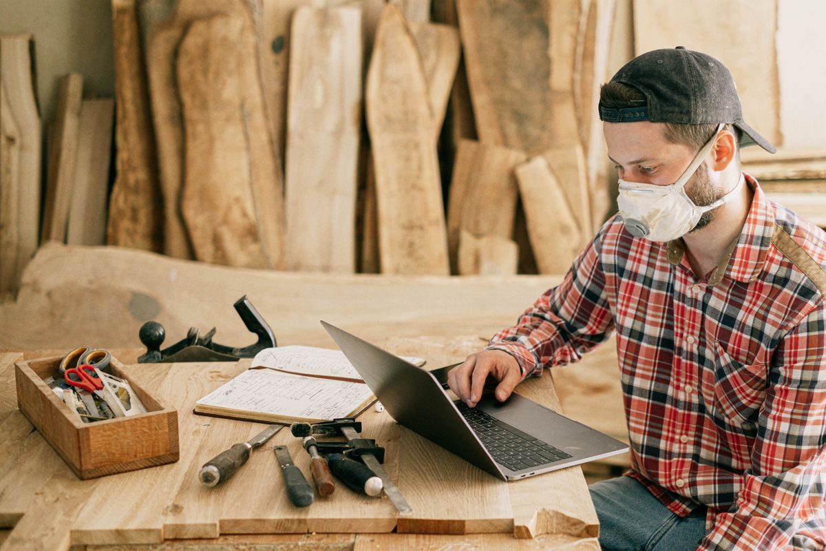 A workbench with hand tools, a laptop and a job written up before the work starts